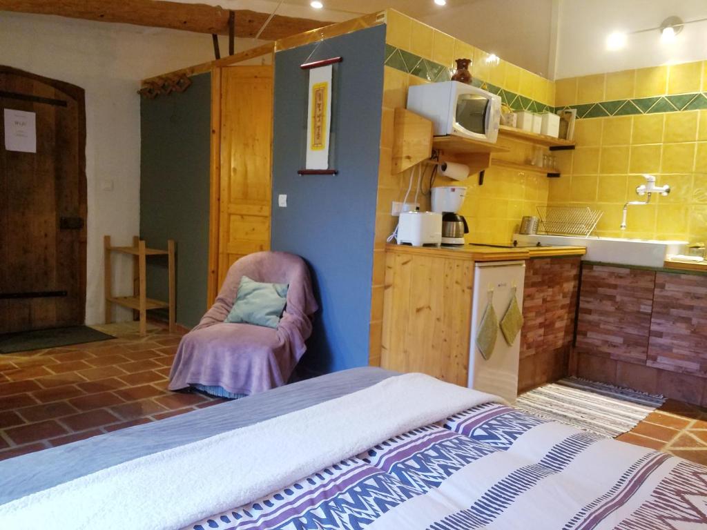 um quarto com uma cama e uma cozinha com azulejos amarelos em Petit Gîte avec SPA en Ariege Montagnes des Pyrénées em Péreille