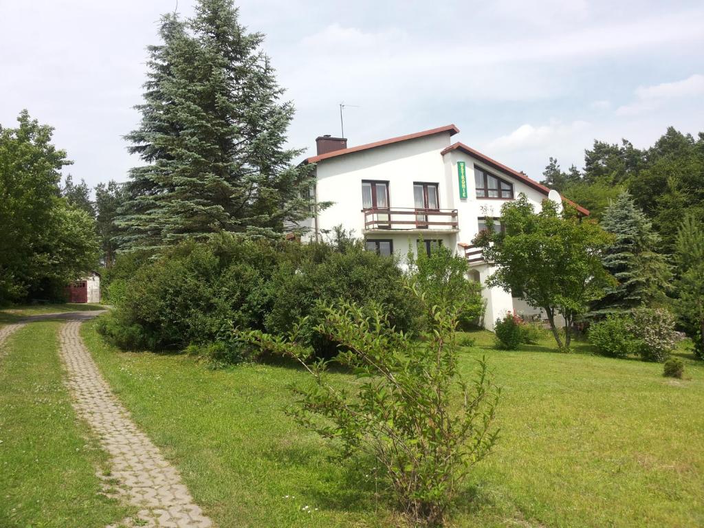 a white house with a path in front of it at Pokoje gościnne Ustronie in Zwierzyniec