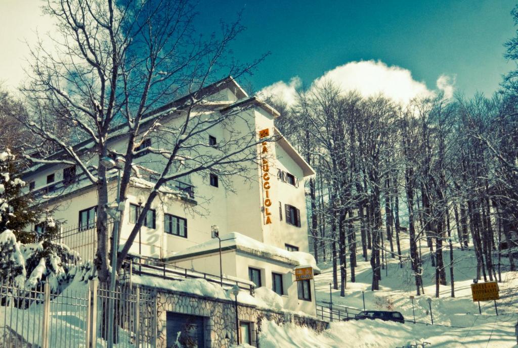 a building with snow on the ground next to trees at Hotel La Lucciola in Terminillo