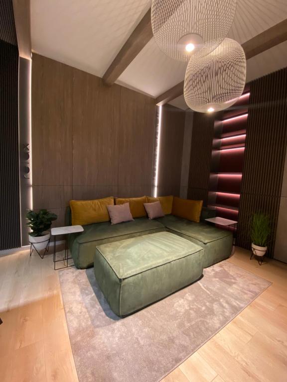 sala de estar con sofá verde y lámpara de araña grande en Art'penthouse, en Brasov