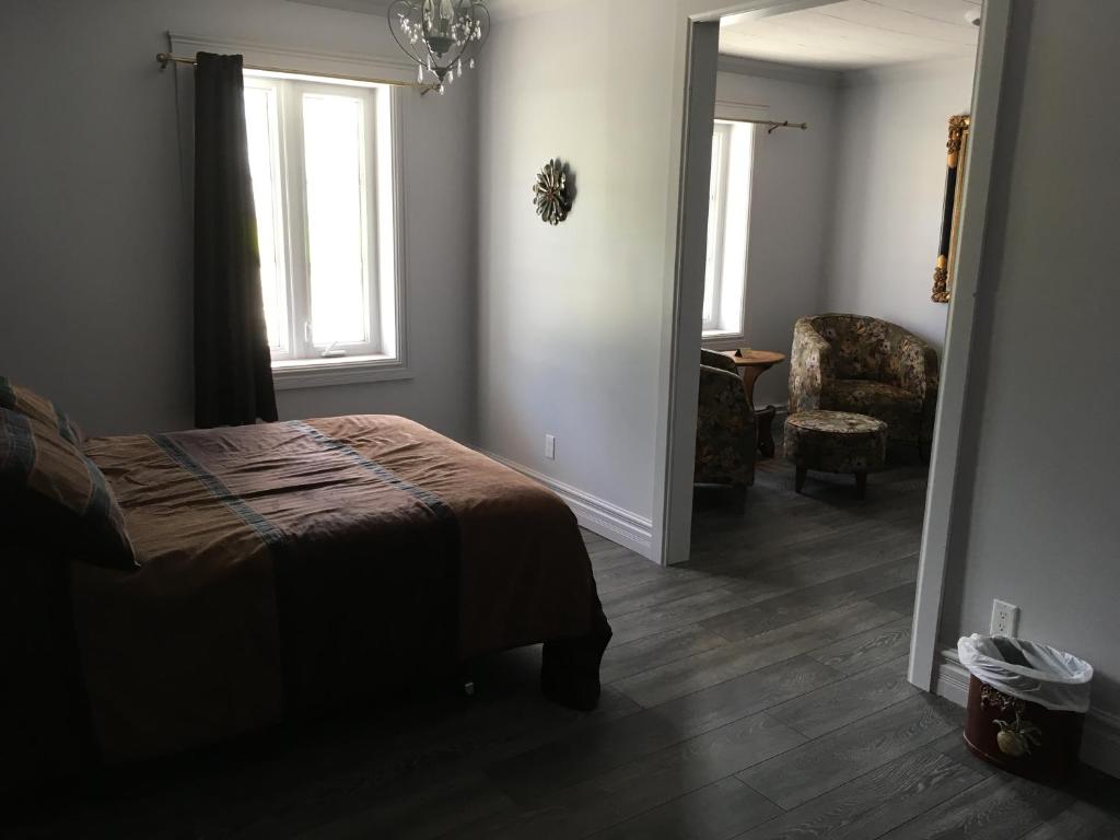 a bedroom with a bed and a chair and a window at Auberge du Vieux Faubourg in Sainte-Anne-des-Monts
