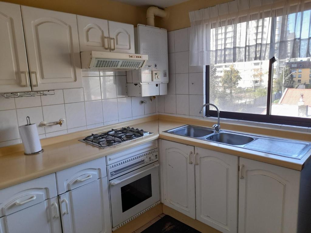 uma cozinha com armários brancos, um lavatório e um fogão em Departamento Temuco Thiers em Temuco