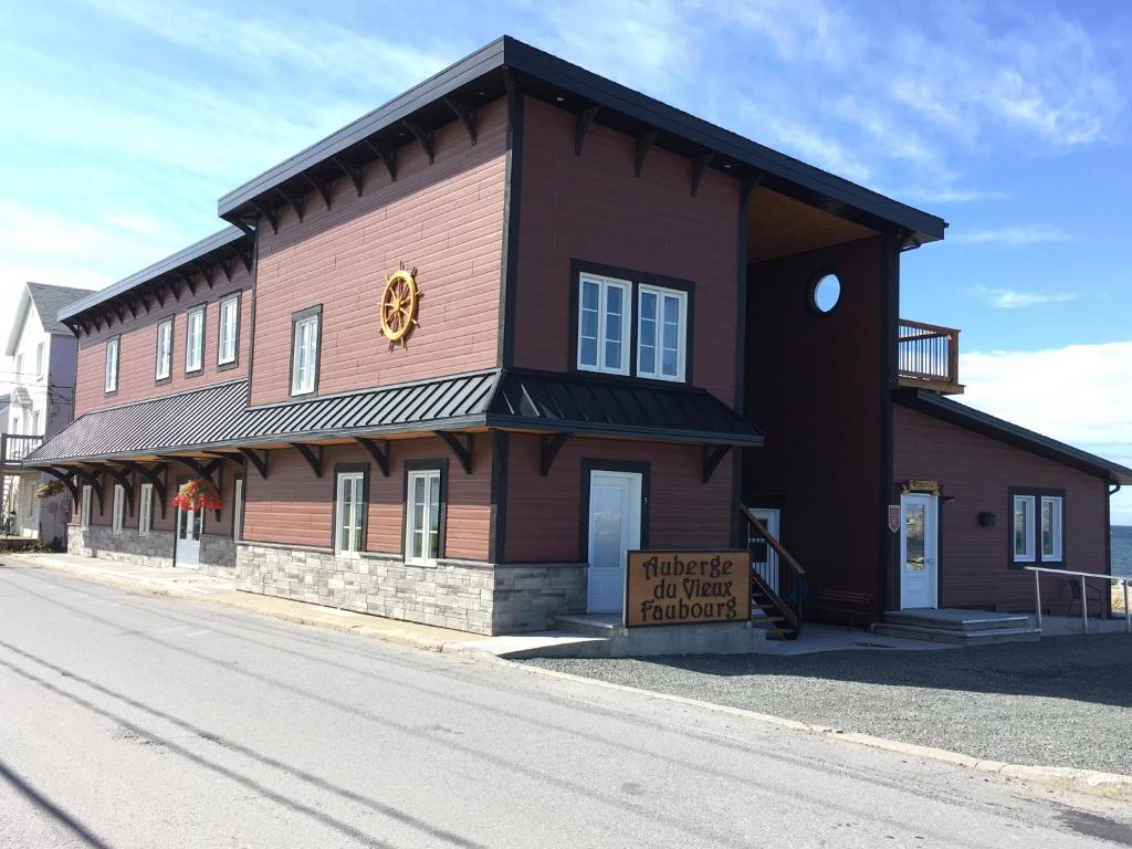 a brown building with a sign in front of it at Auberge du Vieux Faubourg in Sainte-Anne-des-Monts