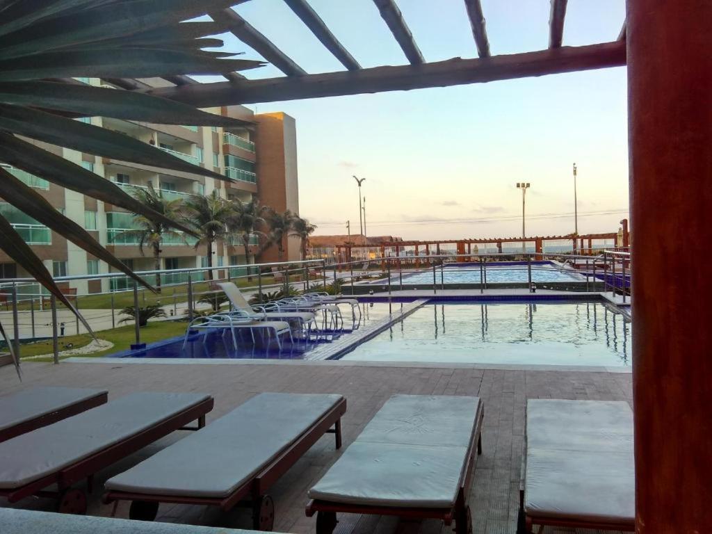 a large swimming pool with benches and a building at VG FUN-OCEAN VIEW BEACH FRONT APARTMENT-Fortaleza in Fortaleza