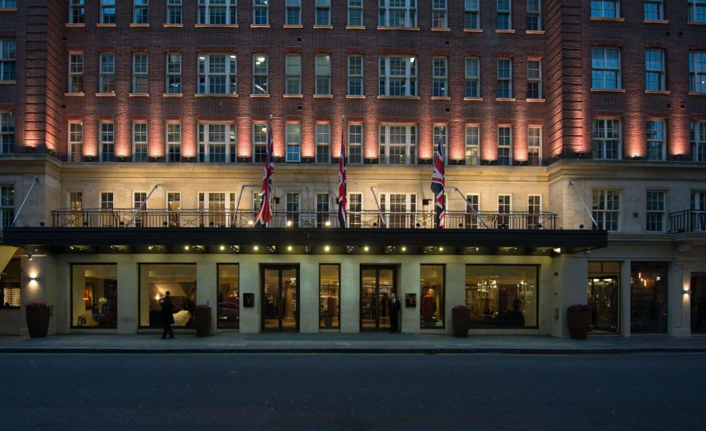 un bâtiment devant lequel se trouve une personne debout dans l'établissement The May Fair, A Radisson Collection Hotel, Mayfair London, à Londres