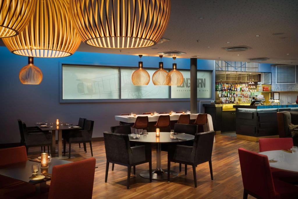 a dining room with tables and chairs and lights at Radisson Blu Hotel, Trondheim Airport in Stjoerdal
