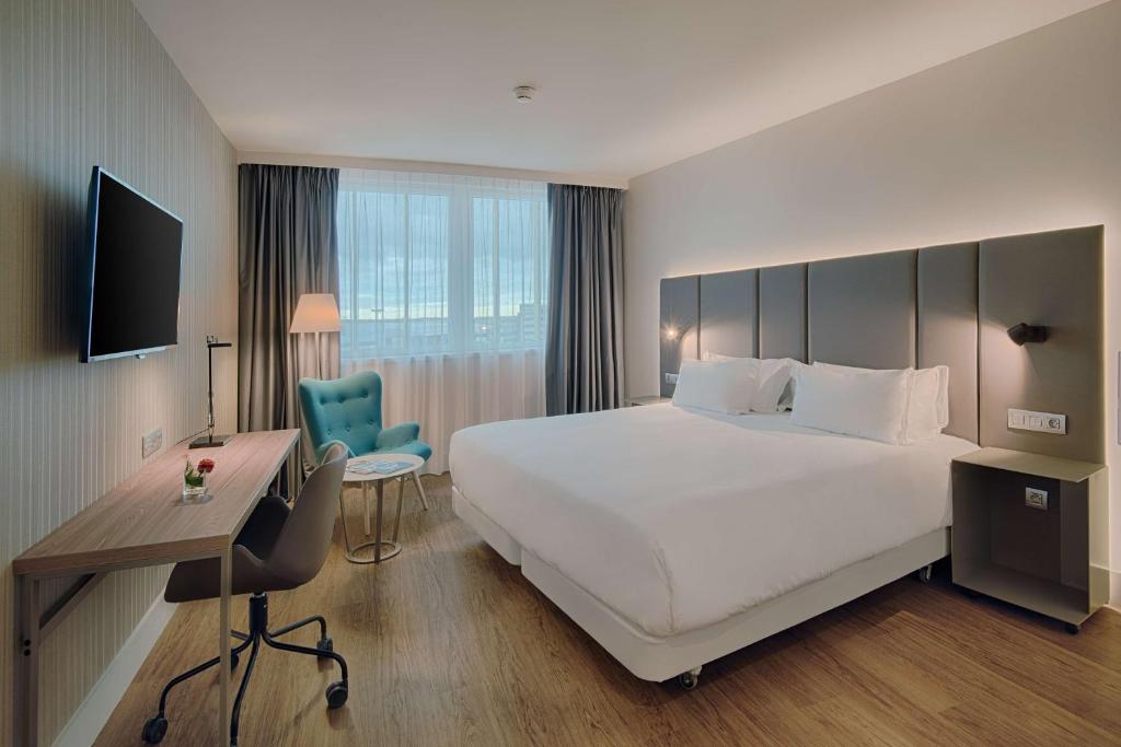 a hotel room with two beds and a television at NH Toulouse Airport in Blagnac