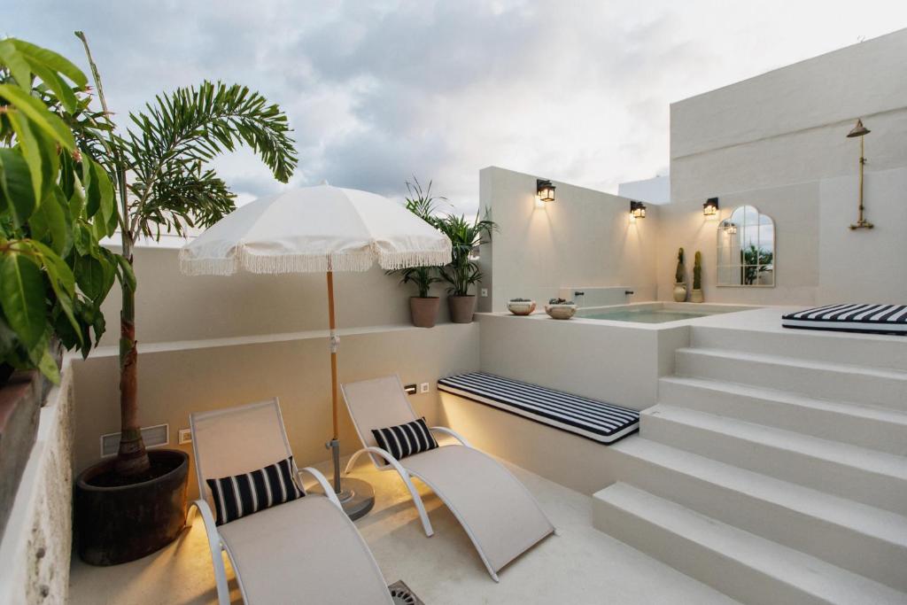 eine Terrasse mit 2 Stühlen und einem Sonnenschirm in der Unterkunft La Colonial Suites Apartamentos de Lujo in Las Palmas de Gran Canaria