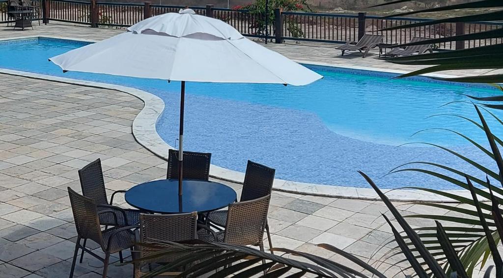 stół z parasolem obok basenu w obiekcie Excelente flat térreo condomínio villa monte castelo w mieście Bezerros