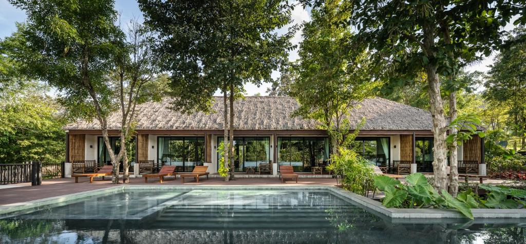 a pool in front of a house with trees at Phapok Eco Resort in Ratchaburi