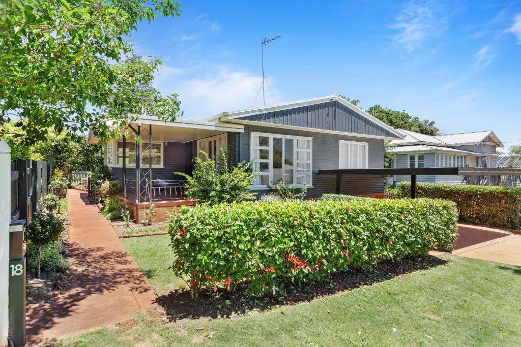 une maison avec une haie devant elle dans l'établissement Artist's Cottage - Cosy Home in Quiet Leafy Street, à Toowoomba
