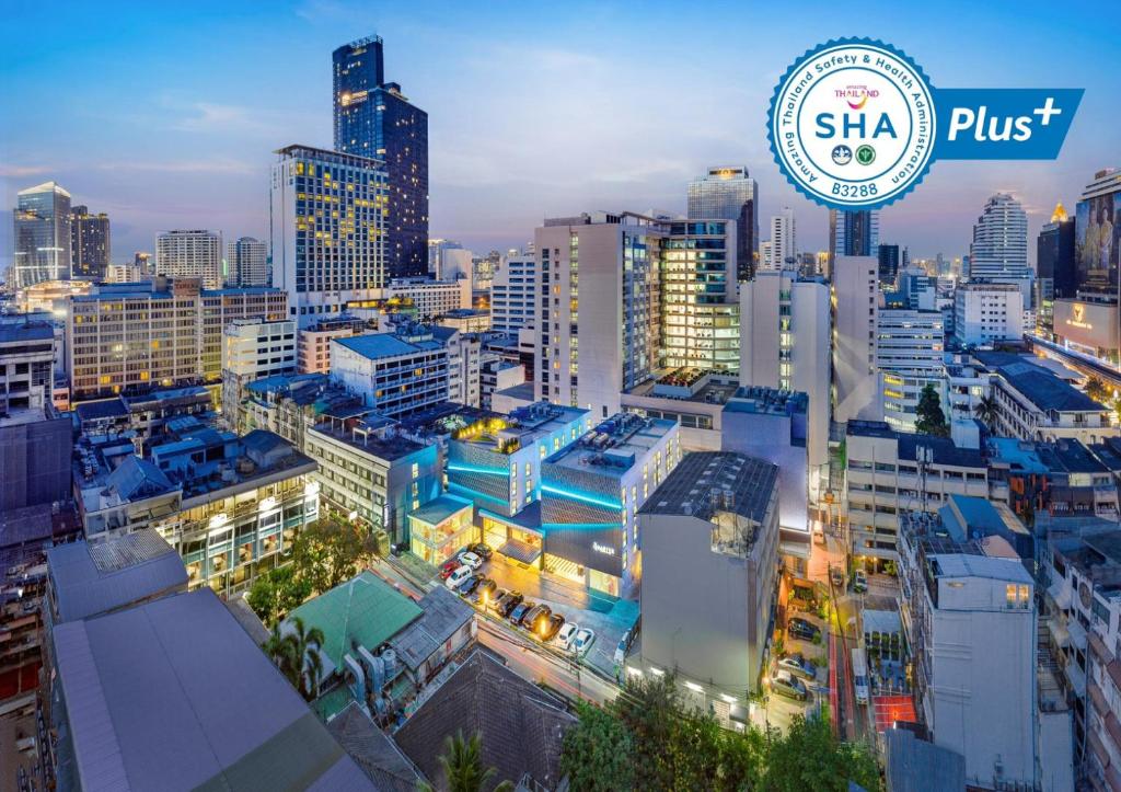 a city skyline at night with a sign for sha plus at The Quarter Silom by UHG in Bangkok