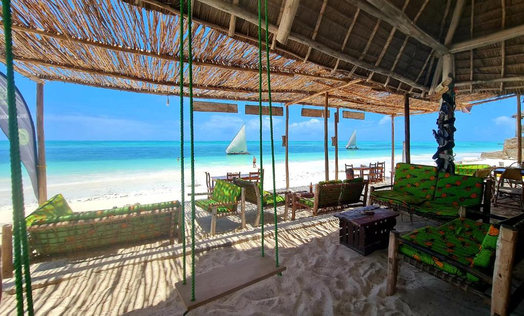 Elle offre une vue sur une plage dotée de chaises et d'un bateau. dans l'établissement Garden Beach Bungalows Jambiani, à Jambiani