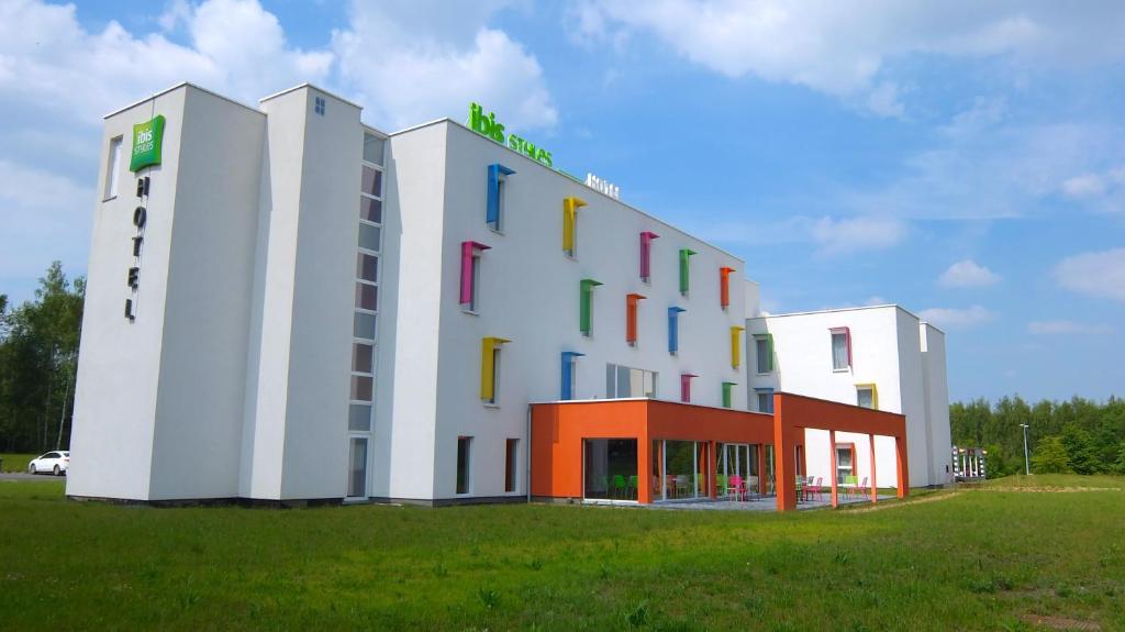 a large white building with colorful windows in a field at ibis Styles Nivelles in Nivelles