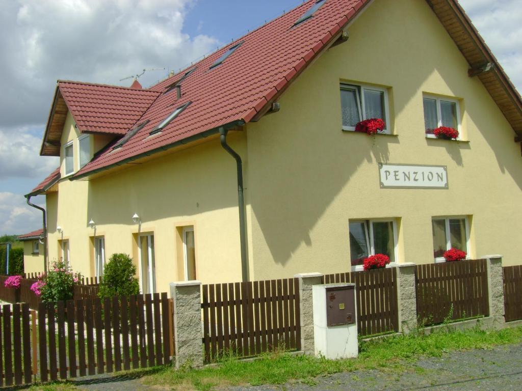 ein gelbes Haus mit rotem Dach und einem Zaun in der Unterkunft Penzion Žírovice in Franzensbad