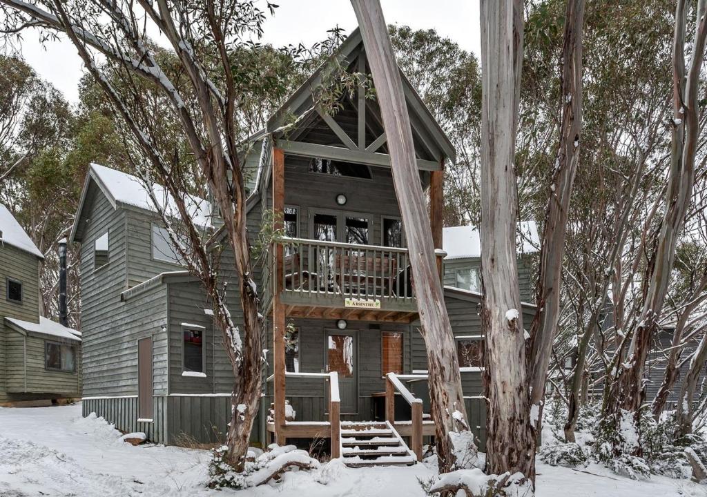 a tree house with a deck in the snow at Absinthe in Dinner Plain