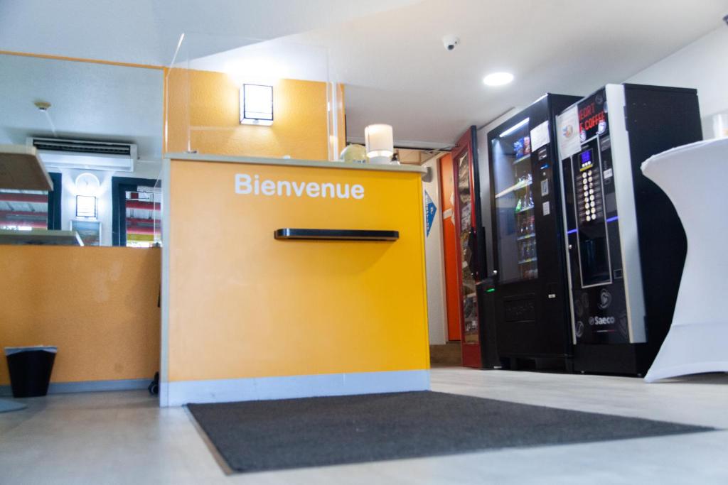 Class'Eco Namur في نامور: آلة بيع صفراء في متجر بجوار آلة المشروبات الغازية