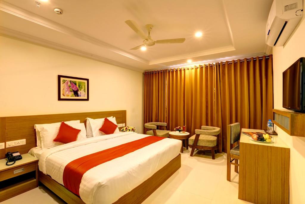 Habitación de hotel con cama y TV en Hotel Floral Park en Kottayam