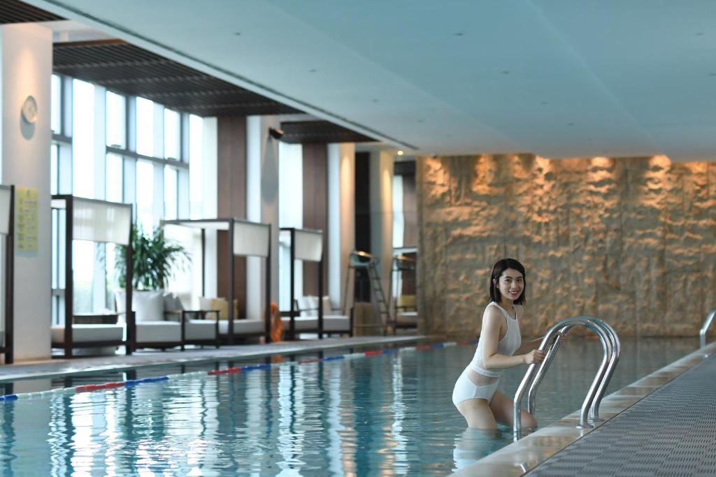 a woman sitting on a rail in a swimming pool at Hyatt Regency Changchun in Changchun