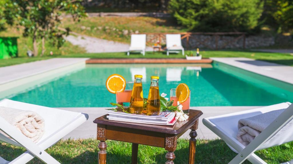 a table with bottles of beer and chairs next to a pool at Casale del Castagneto 8, Emma Villas in Santa Fiora