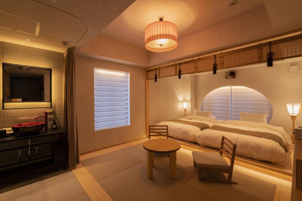 a bedroom with a large bed and a table and chair at moire HOTEL YOSHIWARA in Tokyo