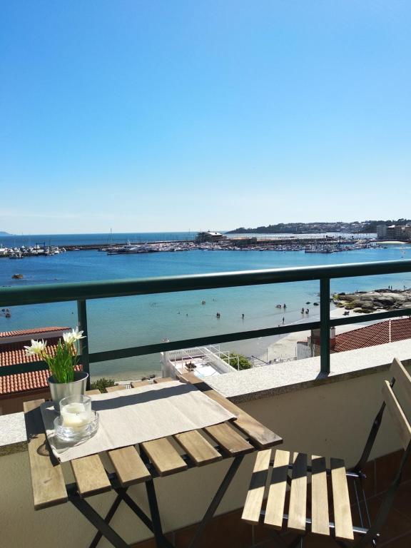 balcón con mesa y vistas a la playa en Precioso ático con vistas a pie de playa, en Sanxenxo