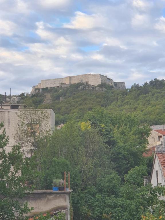 a castle on top of a hill with trees at Apartman Noa in Knin