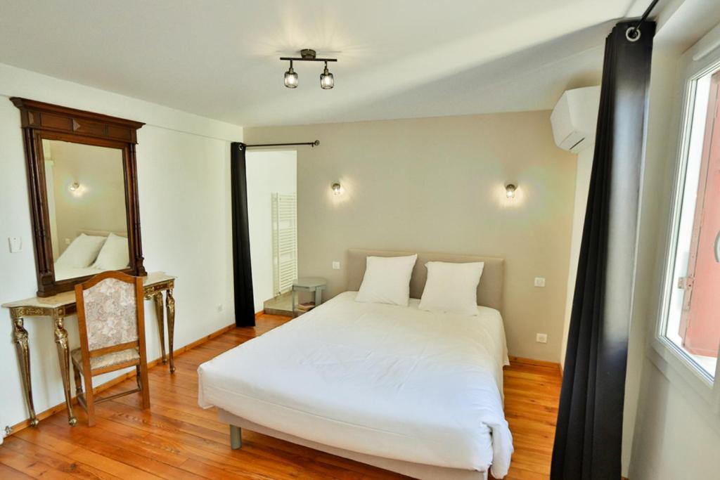 a bedroom with a white bed and a mirror at Le Relais Basque in Hagetmau
