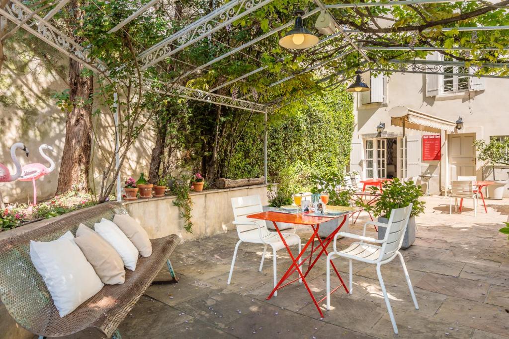 d&#39;une terrasse avec une table, des chaises et une pergola. dans l&#39;établissement Hôtel La Suite, à Villeneuve-lès-Avignon