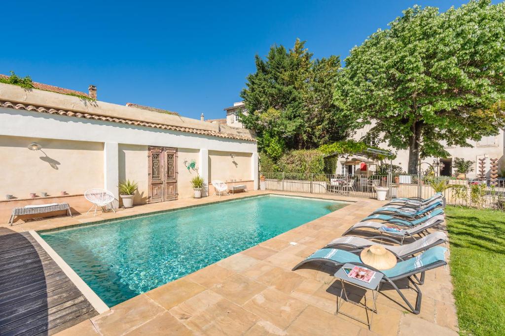 een zwembad met ligstoelen naast een huis bij Hôtel La Suite in Villeneuve-lès-Avignon