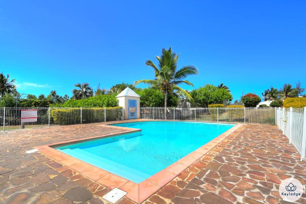 a swimming pool in a yard with a fence and trees at Les Petrels - La Saline-les-Bains in La Saline Les hauts 