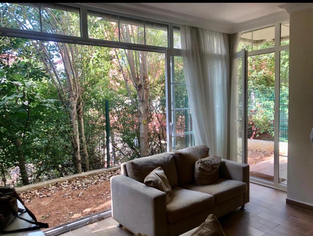 een woonkamer met een bank voor een groot raam bij Lovely Escape House in a Frame with Garden in Istanbul