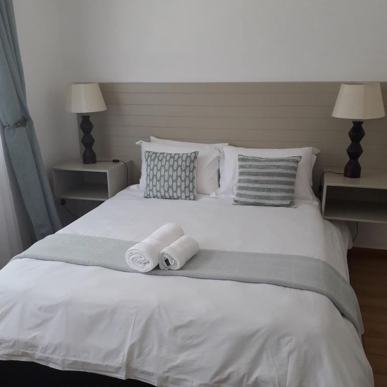 a white bed with two rolled towels on it at Aflica Apartments in Gaborone