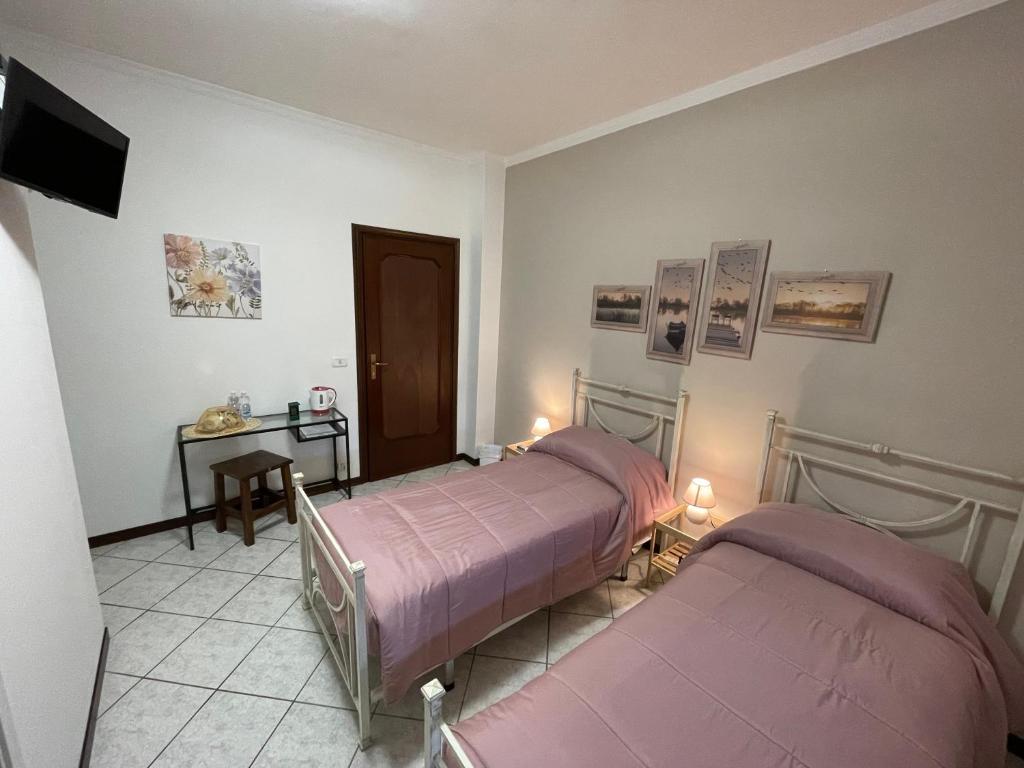a room with two beds and a table and a television at Sole in Gattinara