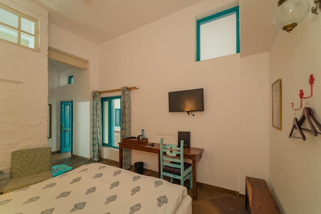a bedroom with a bed and a desk and a television at Mango Tree Courtyard Dehradun in Dehradun