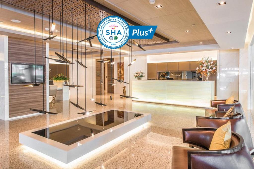 a lobby with leather chairs and a sign that says sheu plus at Qiss Residence by Bliston - SHA Plus in Bangkok