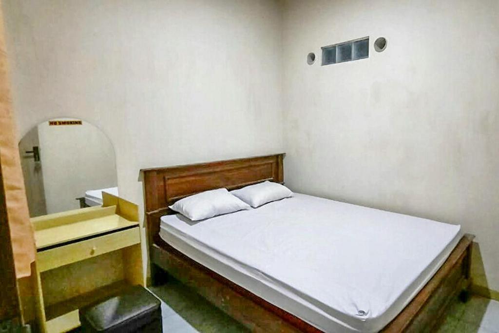 Dormitorio pequeño con cama y espejo en Central House Karimunjawa RedPartner en Karimunjawa