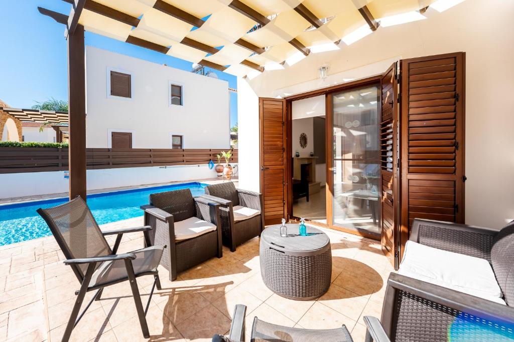 阿依納帕的住宿－Villa Poseidon by Ezoria Villas，一个带椅子的庭院和一个游泳池