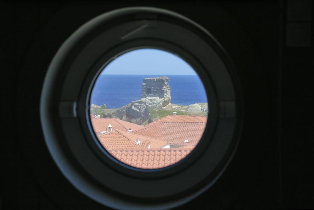a view of the ocean through a round window at Camara Homes in Andros