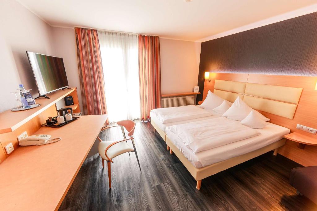 a hotel room with a bed and a desk at Best Western Plaza Hotel Stuttgart-Ditzingen in Ditzingen