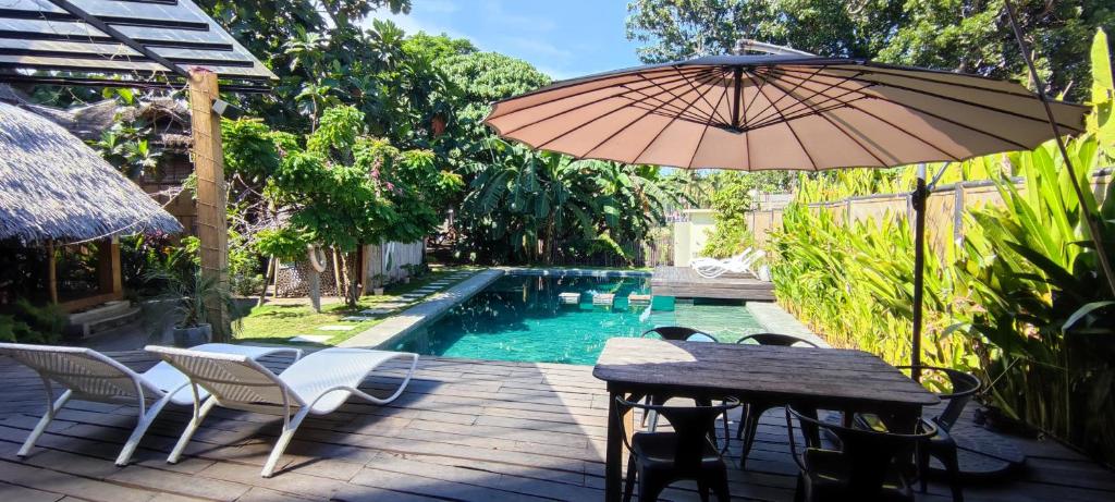 um pátio com uma mesa, um guarda-sol e uma piscina em Bongo Bongo Divers em Dauin