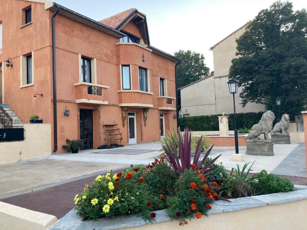 un edificio con una statua e dei fiori di fronte di Hôtel La Demeure Coloniale a Moriani-Plage
