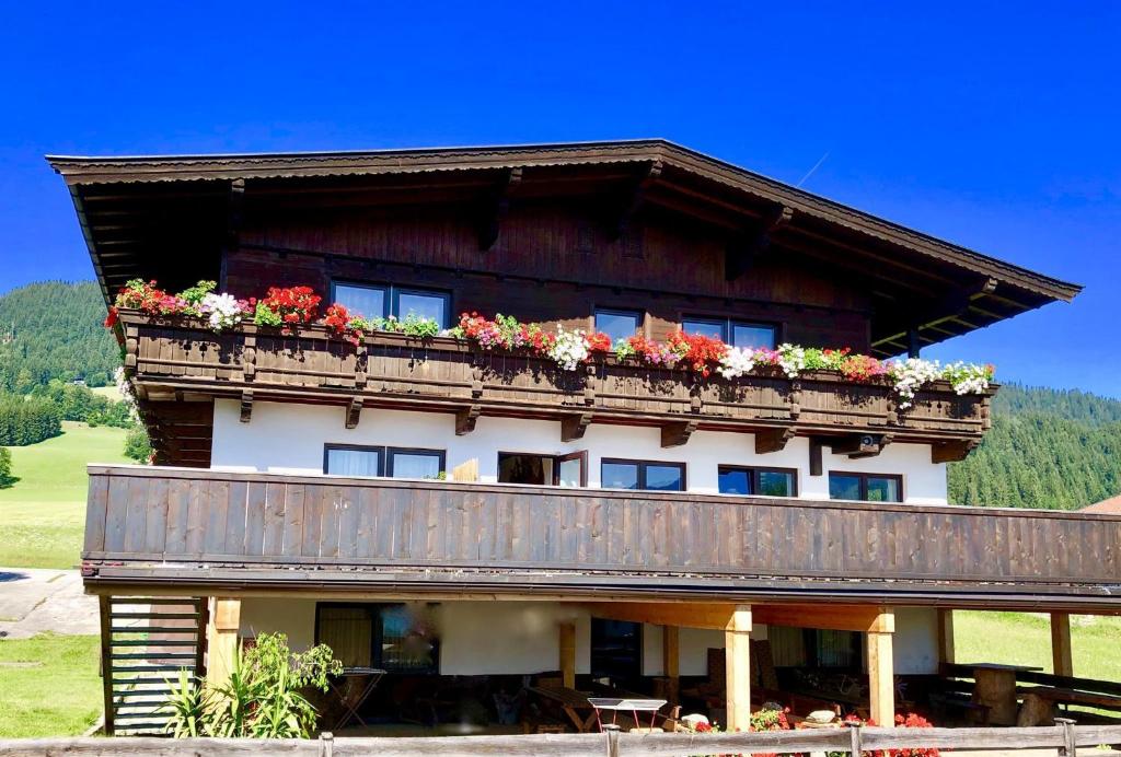 a building with a balcony with flowers on it at Pension Heidelberg - Fam Fuchs in Hopfgarten im Brixental