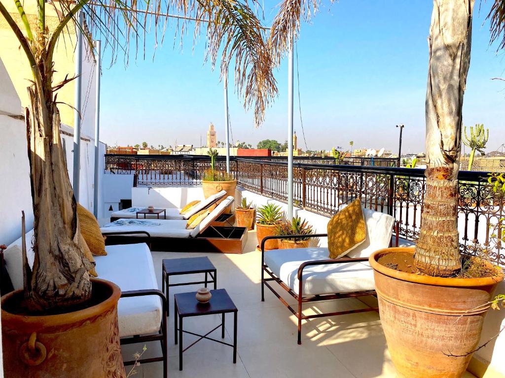 un patio con sillas y palmeras en un balcón en Palais Princesse, en Marrakech