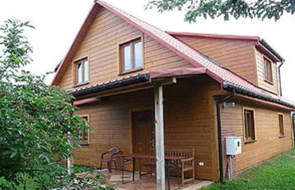 a house with a porch with a table and chairs at Gospodarstwo Agroturystyczne Bobrowa Zagroda in Narewka