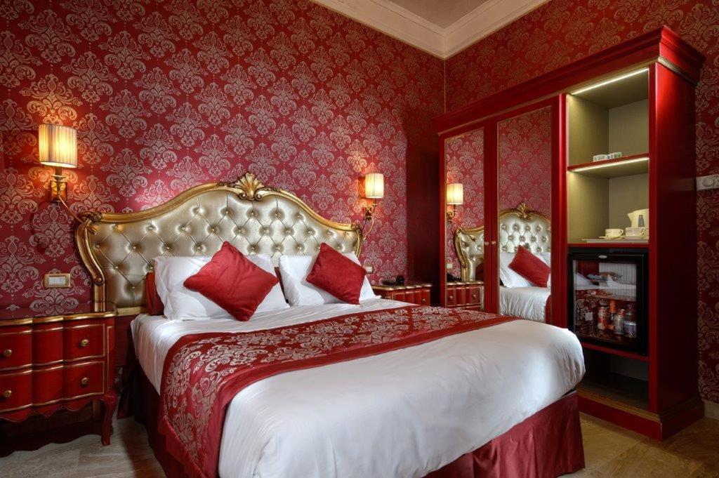 een slaapkamer met een groot bed met rode muren bij Hotel Canaletto in Venetië