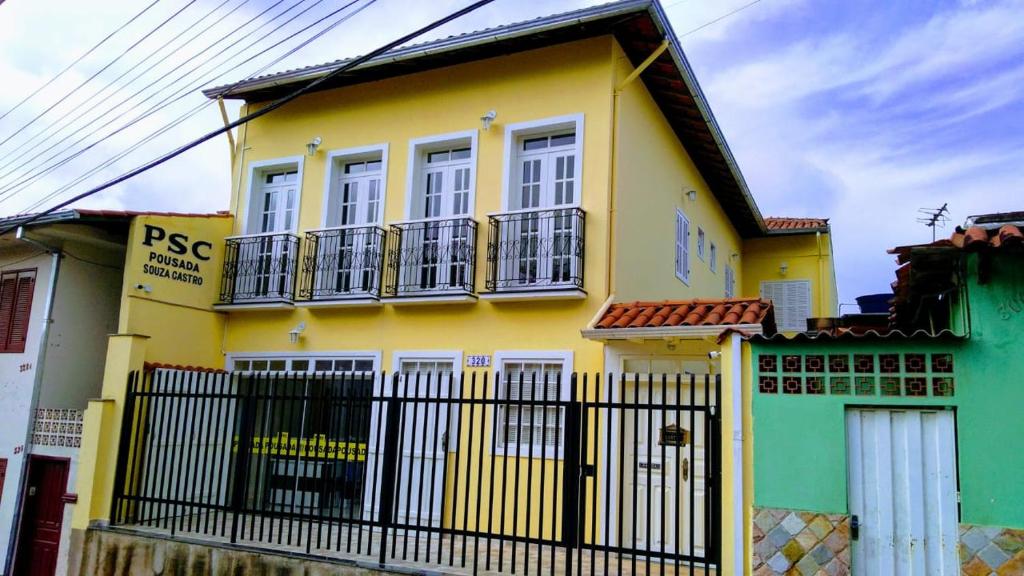 歐魯普雷圖的住宿－Pousada Souza Castro，黄色和绿色的房子,有黑色的围栏