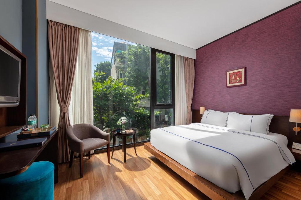 
a hotel room with a bed, chair and a window at Oriana Boutique Hotel & Spa in Hanoi
