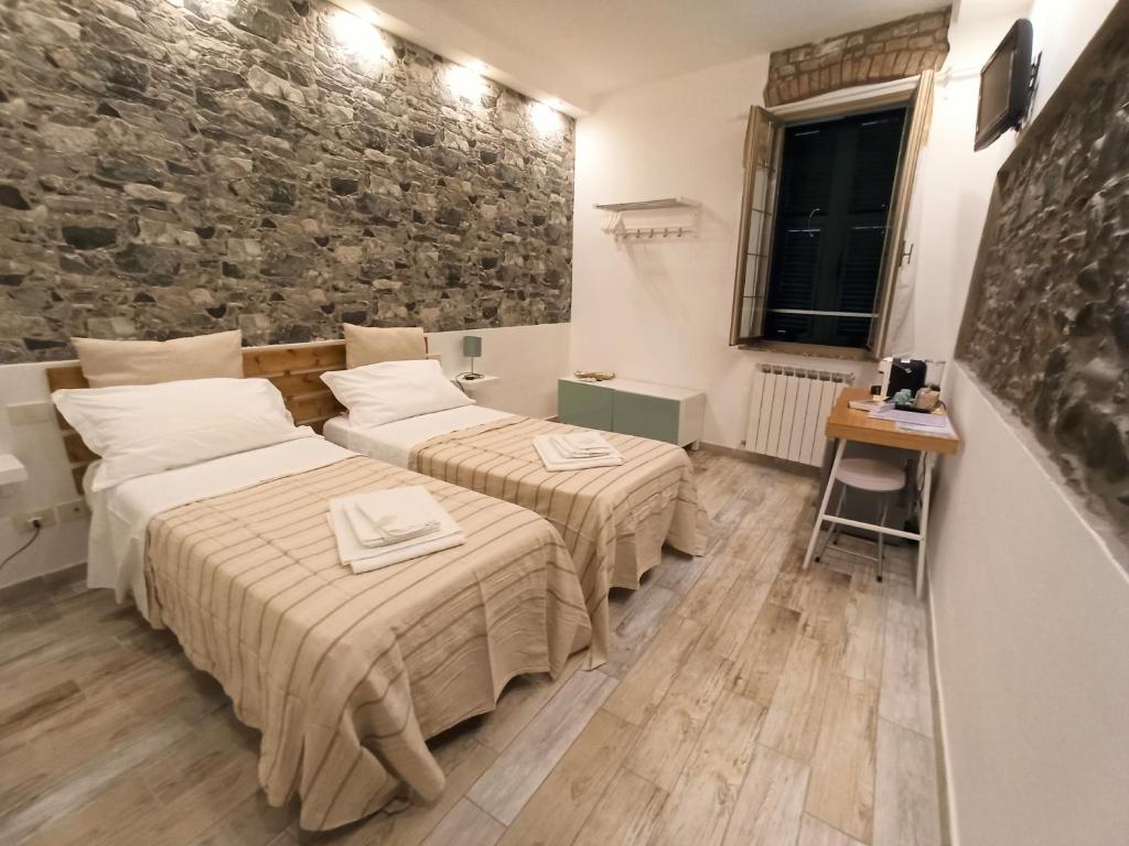 two beds in a room with a stone wall at Affittacamere Albarola in Riomaggiore