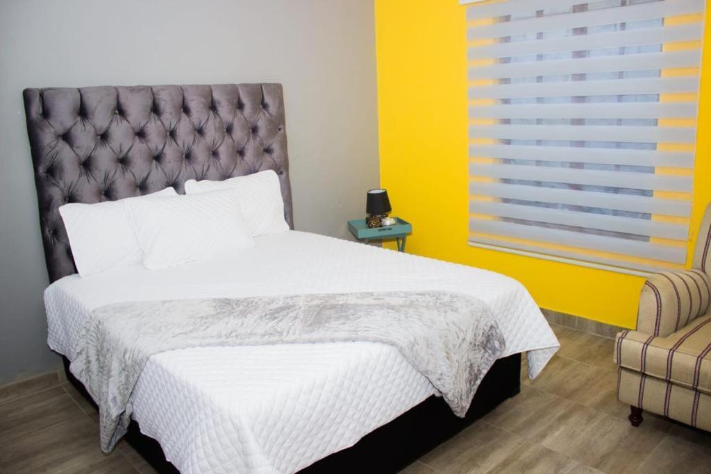 a bedroom with a bed and a yellow wall at Rukza's Guest House in Soweto